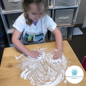 Sierra practices letter formation by drawing in shaving cream.