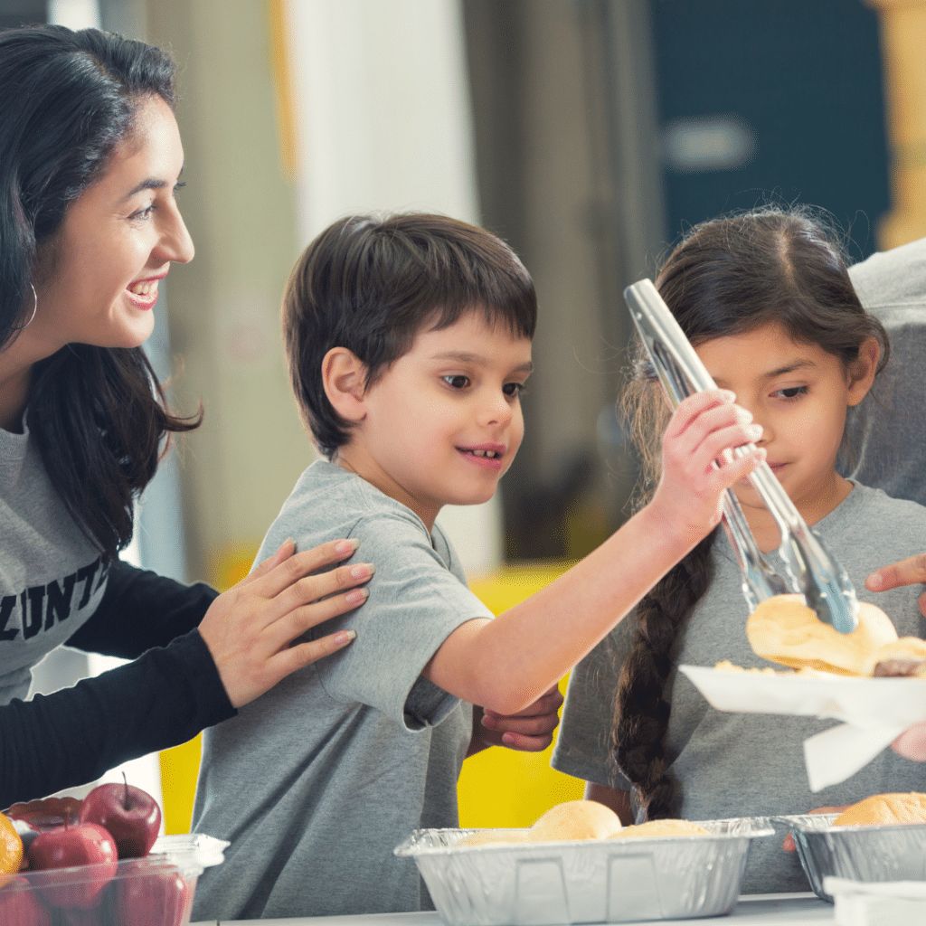 Children serving food using tongs.