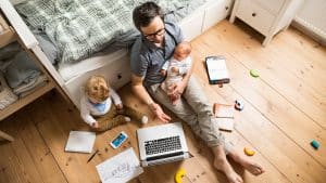 Un padre está trabajando desde casa con sus hijos.