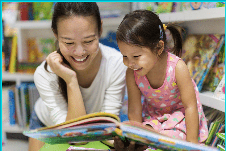 Mother and daughter reading a book aloud 