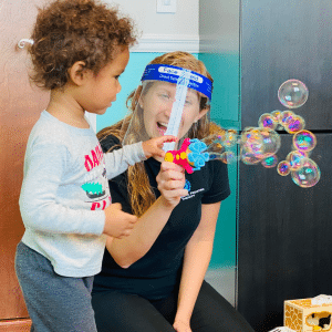 Child and therapist playing with bubbles