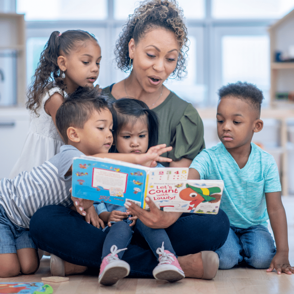 A teacher is reading a book to a group of four children