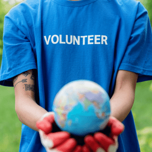 A person wearing a volunteer shirt holding a model Earth