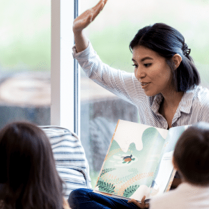 a teacher is raising her hands while reading to a group of children