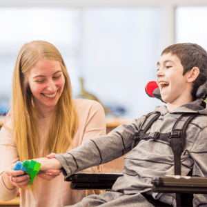 A therapist works on fine motor activities with a child in a wheelchair