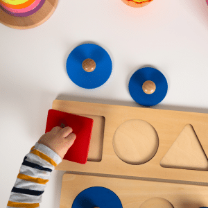 A toddler places a square shape into a puzzle